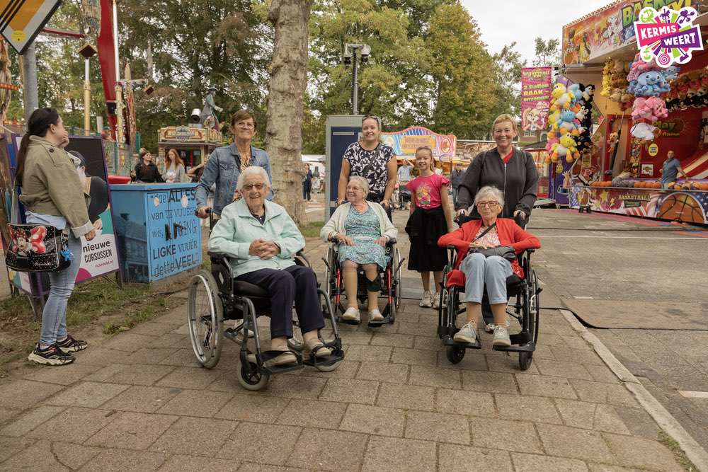 Enkele bezoekers op de prikkelarme kermis, onder andere in een rolstoel. (Klik om de foto te vergroten).